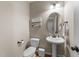 Well-lit half bathroom with a pedestal sink, oval mirror, and decorative painting at 323 Windgate Dr, Clayton, NC 27527