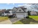 View of the light-green home showing attached garage and manicured lawn on a sunny day at 323 Windgate Dr, Clayton, NC 27527