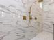 Close-up of a marble tiled shower with gold fixtures, a rainfall showerhead, and modern design elements at 40 Ridgeline Ct # 10, Pittsboro, NC 27312