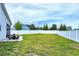 Large backyard featuring a concrete patio with a fire pit, lush green grass, and a privacy fence at 49 Kathy Mae Ct, Angier, NC 27501