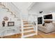 Elegant staircase with hardwood steps and white railings, leading to a cozy living room with fireplace at 5112 Wolcott Ct, Fuquay Varina, NC 27526