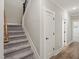 Carpeted staircase with wood handrail, next to a white door and hardwood floors in a modern home at 60 Heart Pine Dr, Wendell, NC 27591