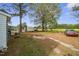 Large, grassy backyard with mature trees, sheds, and car parked on gravel at 607 E Granville St, Dunn, NC 28334