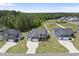 Aerial view of a landscaped home with well-manicured lawn, three car garage, and a wooded backdrop at 86 Buckhaven Ct, Holly Springs, NC 27540