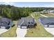 Aerial view of a landscaped home with well-manicured lawn, three car garage, and a wooded backdrop at 86 Buckhaven Ct, Holly Springs, NC 27540
