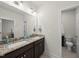 Bathroom with double sinks, granite counters, dark wood cabinets, framed mirror, and separate toilet area at 86 Buckhaven Ct, Holly Springs, NC 27540