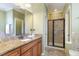 Bathroom with double sink vanity, granite countertops, and tiled shower at 9207 Wooden Rd, Raleigh, NC 27617