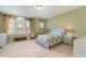 Bedroom with large windows, carpet, neutral walls, and traditional furnishings at 9207 Wooden Rd, Raleigh, NC 27617
