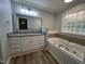 Bathroom featuring double vanity with granite countertop, soaking tub, plank flooring, and decorative mirror at 10017 Oakley Rd, Zebulon, NC 27597