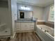 Bathroom featuring double vanity with granite countertop, soaking tub, plank flooring, and glassblock window at 10017 Oakley Rd, Zebulon, NC 27597