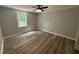 Bright bedroom featuring wood-look floors, a ceiling fan, and a window providing ample natural light at 10017 Oakley Rd, Zebulon, NC 27597