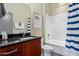 Bathroom featuring wood vanity, granite countertops, and a shower/tub with blue striped curtain at 101 Morris St # D, Durham, NC 27701