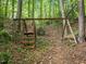 Wood swing set in a private backyard surrounded by lush forest trees and vegetation at 106 Birkhaven Dr, Cary, NC 27518