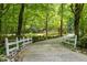 Long driveway with white fences leading to a home surrounded by mature trees, offering privacy and curb appeal at 106 Birkhaven Dr, Cary, NC 27518