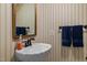 Well-lit powder room featuring elegant sink, wallpaper, and decorative mirror at 106 Birkhaven Dr, Cary, NC 27518