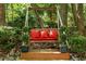Comfortable wooden swing with red pillows nestled among lush trees and greenery, perfect for relaxation at 106 Birkhaven Dr, Cary, NC 27518