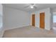 Bedroom featuring a ceiling fan, two closets with wood doors and neutral carpet, complemented by a window at 1105 Hargrove St, Henderson, NC 27536