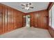 Living room features wood paneling, a ceiling fan, and an open doorway to the kitchen at 1105 Hargrove St, Henderson, NC 27536