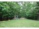 Lush green backyard with playset and stone firepit with Adirondack chairs, perfect for entertaining at 1108 Kalworth Rd, Wake Forest, NC 27587