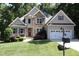 Beautiful home with stone and gray siding, a two-car garage, manicured lawn, and colorful landscaping at 1108 Kalworth Rd, Wake Forest, NC 27587