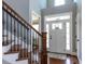 Open foyer with hardwood floors, a staircase with wrought iron railings, and a well lit entry door at 1108 Kalworth Rd, Wake Forest, NC 27587
