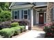 Front entrance featuring a charming doorway framed by stone accents, lush landscaping, and blooming flowers at 1108 Kalworth Rd, Wake Forest, NC 27587