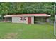Exterior view of a small building or shed, featuring a red metal roof and lean-to on a large lawn at 113 Gulf Drive Dr, Dunn, NC 28334