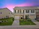 Charming townhome featuring a stone facade, attached garage, and well-manicured landscaping at dusk at 1141 Amber Shadow Dr # 101, Durham, NC 27703