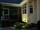 Backyard view featuring a screened porch and manicured garden area with landscape lighting at 115 Oak Leaf Trl, Youngsville, NC 27596