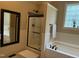 Bright bathroom featuring soaking tub, glass-enclosed shower, and decorative accents at 115 Oak Leaf Trl, Youngsville, NC 27596
