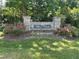 Stone community entrance sign amidst vibrant greenery and flower beds at 115 Oak Leaf Trl, Youngsville, NC 27596