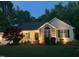 Inviting home exterior illuminated at dusk, highlighting stone accents and manicured landscaping at 115 Oak Leaf Trl, Youngsville, NC 27596