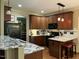 Well-appointed kitchen with dark wood cabinetry, granite counters, and a breakfast bar with seating at 115 Oak Leaf Trl, Youngsville, NC 27596