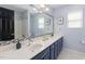 Stylish bathroom with a double sink vanity, decorative mirror, and light blue walls at 1220 Marbank St, Wake Forest, NC 27587