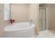 Corner soaking tub and glass enclosed shower with natural light from a window at 1220 Marbank St, Wake Forest, NC 27587