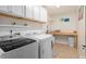 Well-lit laundry room with white cabinets, open shelving, and new washer and dryer at 1220 Marbank St, Wake Forest, NC 27587