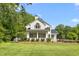 Charming white home with lots of windows surrounded by lush greenery and well-manicured lawn at 1925 W Lake Dr, Burlington, NC 27215