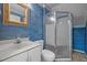 Compact bathroom with blue accent wall, toilet, sink, mirror, and glass door shower at 206 Swiss Lake Dr, Cary, NC 27513