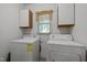 Laundry room with washer, dryer, window, and upper cabinets at 206 Swiss Lake Dr, Cary, NC 27513