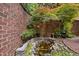 Custom brick wall and pond area with decorative rock border and mature foliage in backyard at 213 Old Franklin Grove Dr, Chapel Hill, NC 27514