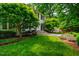 Manicured lawn and landscaping, leading to this home's stone walkway to the front door, and surrounded by mature trees at 220 Glandon Dr, Chapel Hill, NC 27514