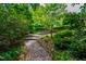 A stone path meanders through a lush garden towards a house with stone stairs and retaining wall at 220 Glandon Dr, Chapel Hill, NC 27514