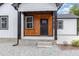 Inviting front porch with stained wood accent wall, black door and black trim at 2616 Wedgedale Ave, Durham, NC 27703