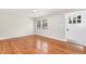 Bright living room with gleaming hardwood floors, a window, and a white door at 2616 Wedgedale Ave, Durham, NC 27703