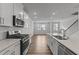 Modern kitchen features stainless steel appliances, a center island, white cabinets, and hardwood floors leading to the living area at 2617 Chert Ln, Raleigh, NC 27610