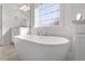 White soaking tub in a bathroom with double sinks and large window allowing natural light at 330 Macallan Dr, Burlington, NC 27215