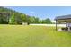 Spacious backyard with a manicured lawn, white fence, shed, and a covered patio, offering ample space for recreation at 3345 Little Creek Church Rd, Clayton, NC 27520