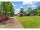 A beautiful home with a long driveway, lush greenery, and landscaping on a bright, sunny day at 4612 River Farm Rd, Rocky Mount, NC 27803