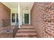 Inviting front entrance with brick steps leading to a green door, complemented by exterior lighting at 4612 River Farm Rd, Rocky Mount, NC 27803