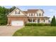 Charming two-story home with a brick-accented garage and a welcoming front porch with manicured landscaping at 48 Falling Oak Ct, Clayton, NC 27520